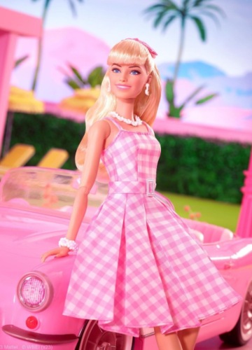 Barbie muñeca apoyada en un coche rosa