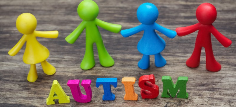 psicología y autismo. Muñecos de colores frente a la palabra autismo en inglés.