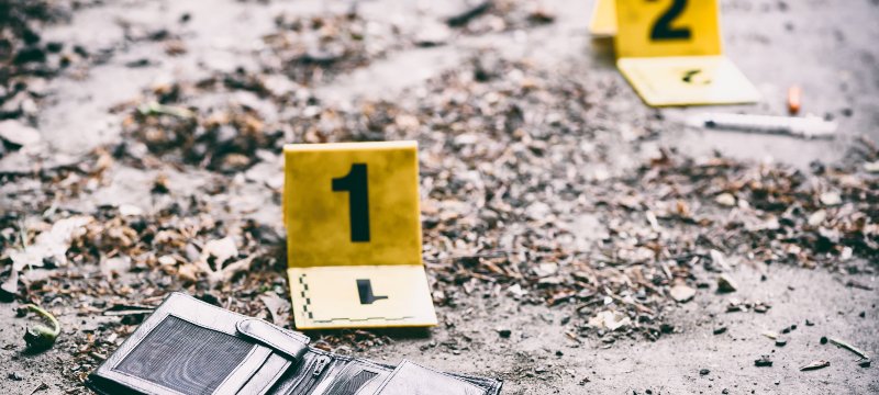 Dos marcadores de pruebas en el escenario de un crimen, uno de ellos en una cartera.