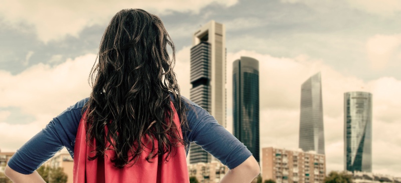 Mujer de espaldas mirando una ciudad con un traje de superman