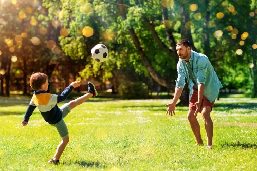 niño y padre jugando al fútbol