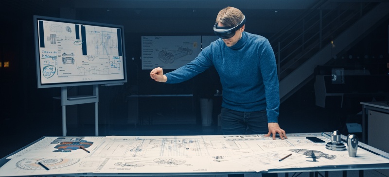 Arquitectura e informática. Un hombre con gafas 3D frente a una mesa de arquitectura.