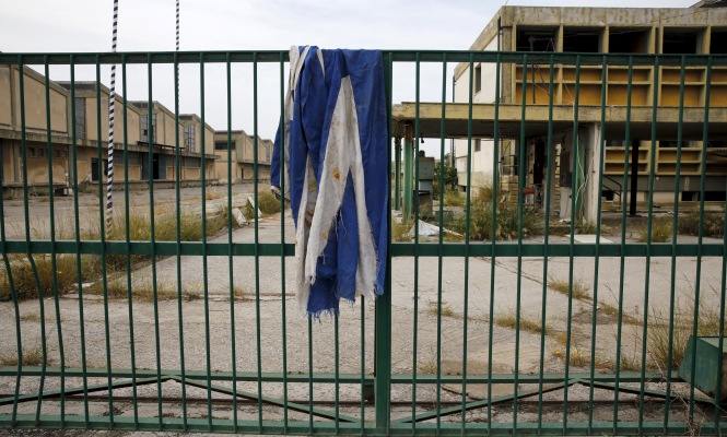 La bandera de Grecia aparece sucia y rasgada en la valla de una fábrica abandonada