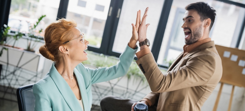 Buen rollo en el trabajo dos personas dándose una palmada de buen trabajo.