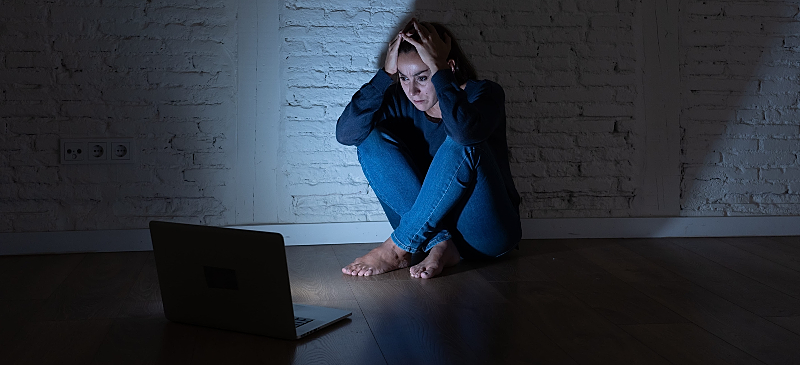 Mujer asustada frente a un ordenador por recibir contenidos amenazantes