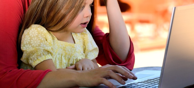 Niña pequeña aprendiendo ante un ordenador con una adulta