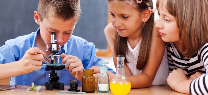 Niños científicos en el laboratorio con el microscopio