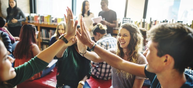 Grupo de jóvenes contentos chocándose las manos