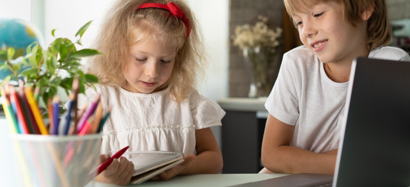 Dos niños consultando un blog de notas frente al ordenador