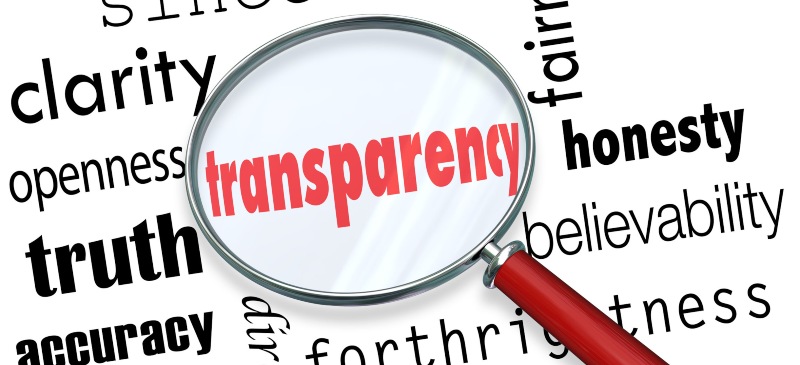 la palabra transparencia en inglés bajo una lupa rodeada de otras palabras como verdad, honestidad...