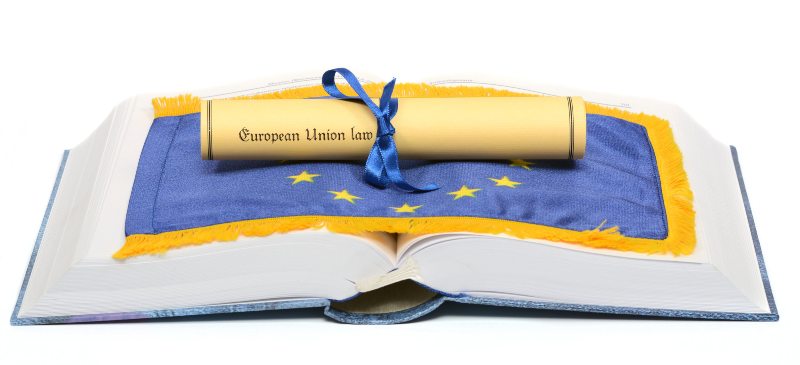Libro de derecho de la Unión Europea con un diploma y la bandera de la unión.