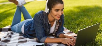 Alumna en el césped conectándose online para estudiar