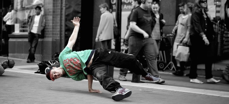 B-Boy bailando en plena calle mientras la gente pasa a su alrededor