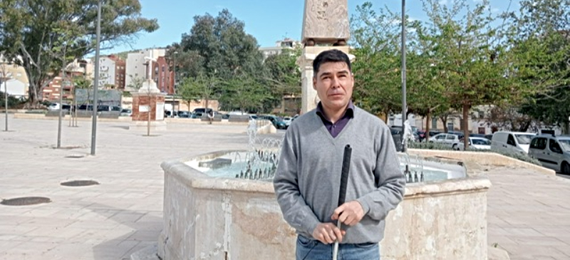 Carlos Cuevas en un parque con una fuente detrás