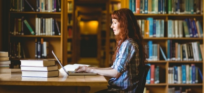 Alumna universitaria estudiando en una biblioteca.