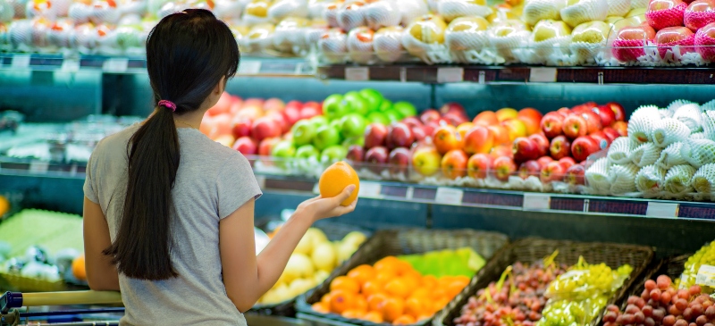 Chica eligiendo fruta en el supermercado
