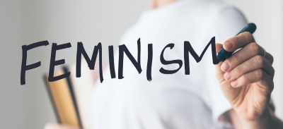 Mujer escribiendo la palabra feminismo en una pantalla de cristal