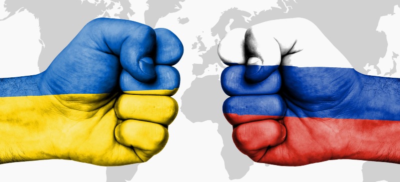 puños enfrentados con las banderas de Ucrania y Rusia