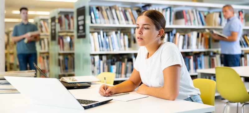 Mujer en una biblioteca preparando oposiciones