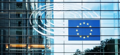 Fotografía del exterior del Parlamento Europeo con la imagen de la bandera de la Unión Europea reflejada en la cristalera