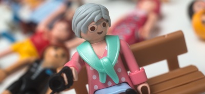 figura de mujer sentada en banco y detrás personas en suelo