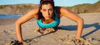 Mujer deportista haciendo flexiones en la playa